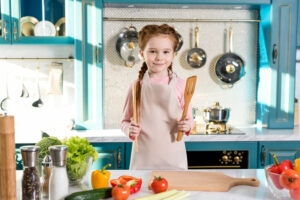 adorable child in apron holding wooden utensils an 2022 12 16 17 39 47 utc